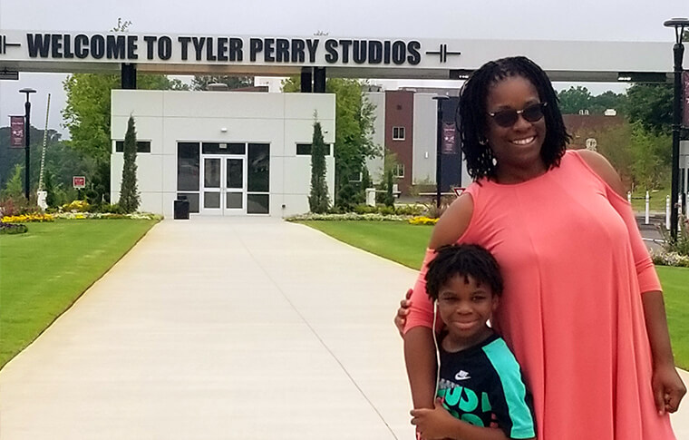 Woman and young boy in front of Tyler Perry Studios